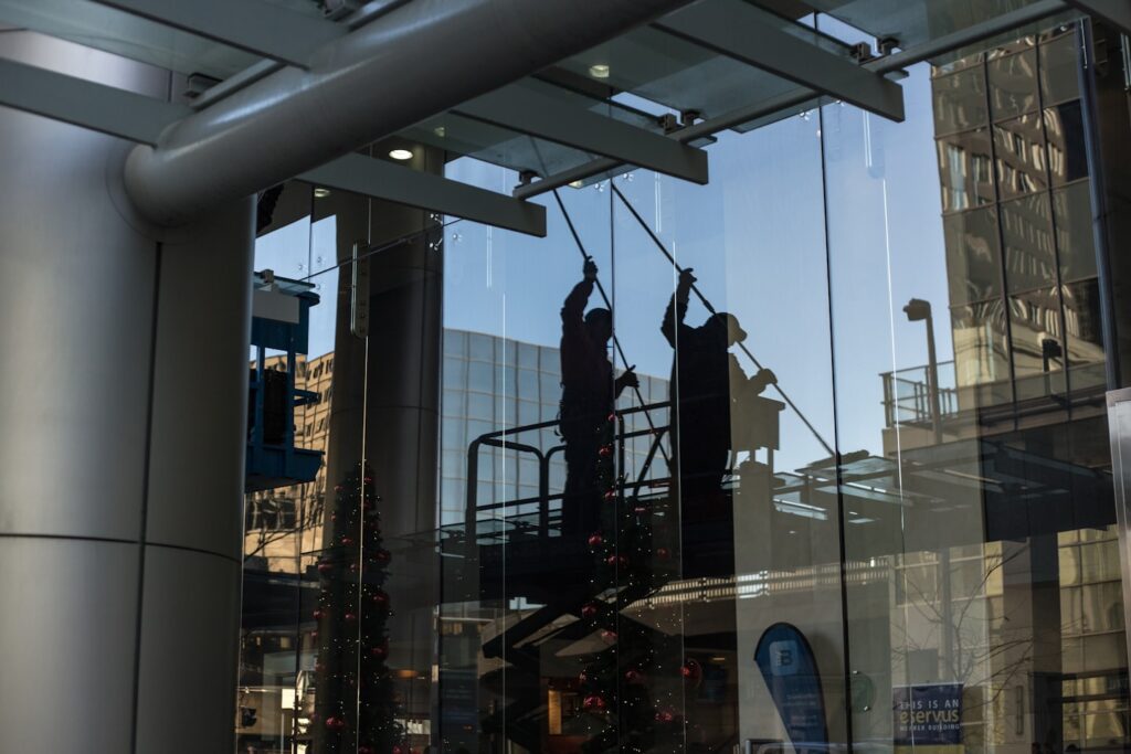 Homme sur une nacelle qui nettoie une vitrine avec une raclette