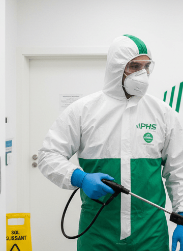 Agent de la société de phs nettoyage (vert et blanc) avec un masque nettoie une clinique