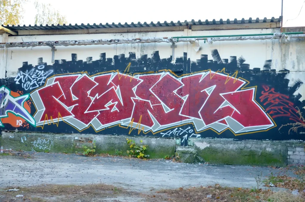 Mur avec un graffitis d'écriture rouge et rose dessus